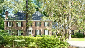Brick house surrounded by trees and greenery.
