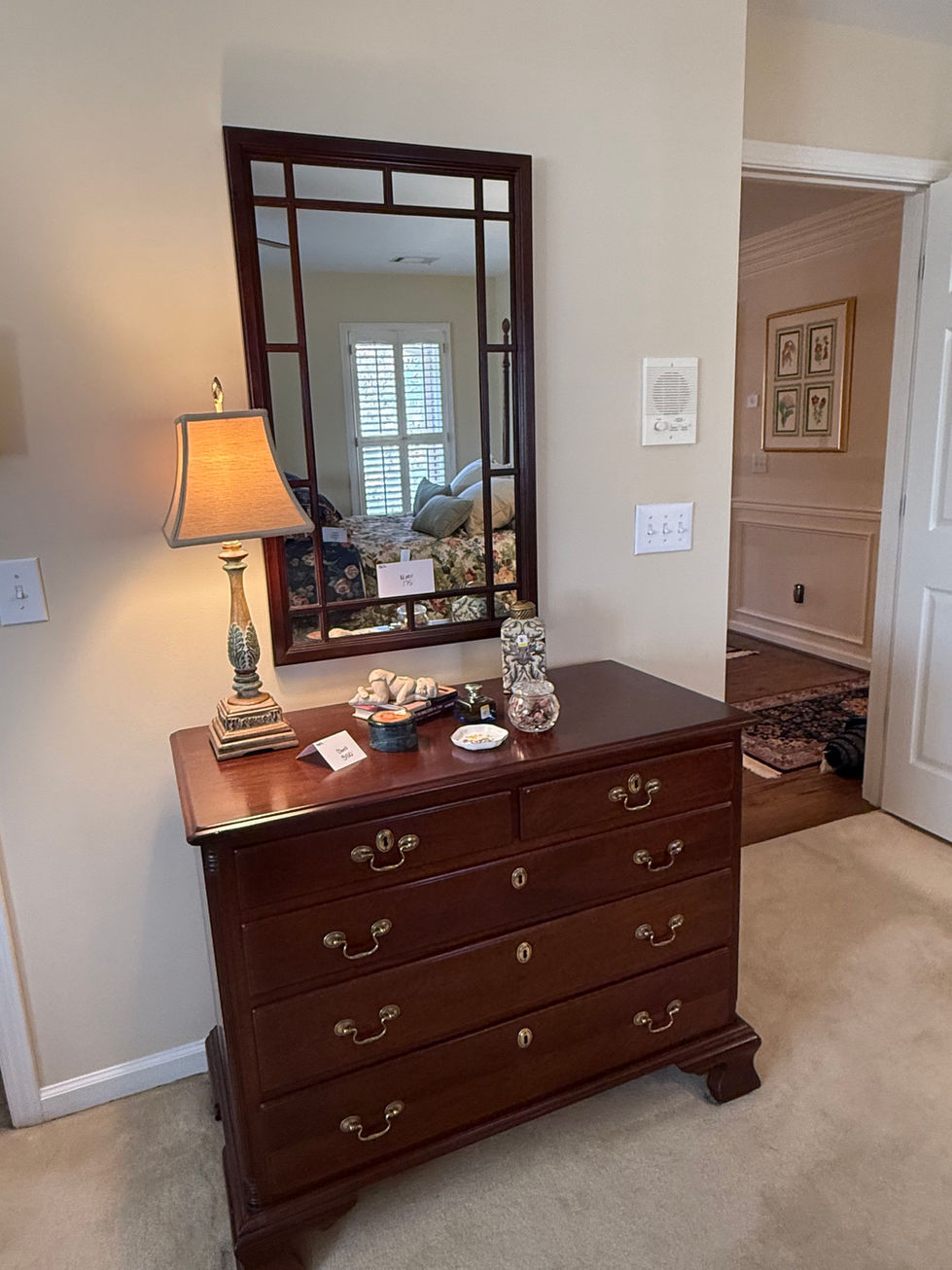 a bedroom with a dresser a lamp and a mirror