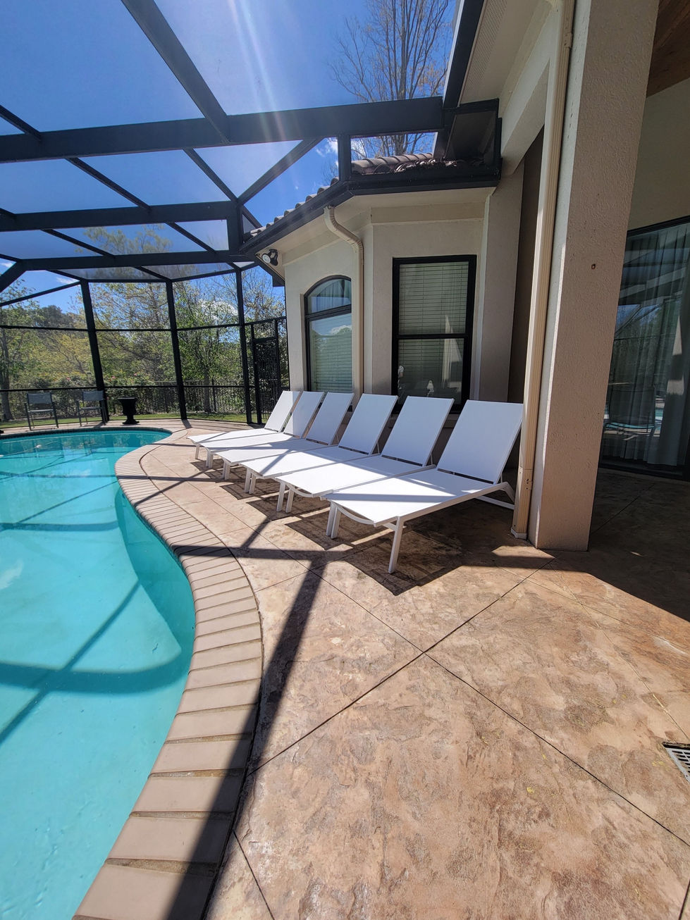 a row of white lounge chairs sit next to a swimming pool