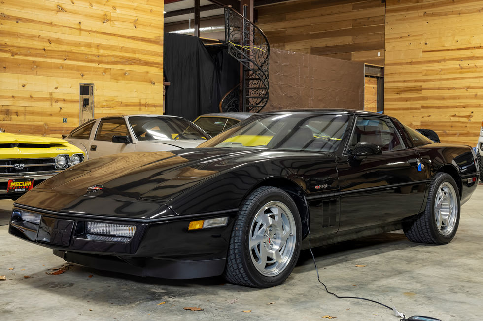 a black corvette is parked in a garage