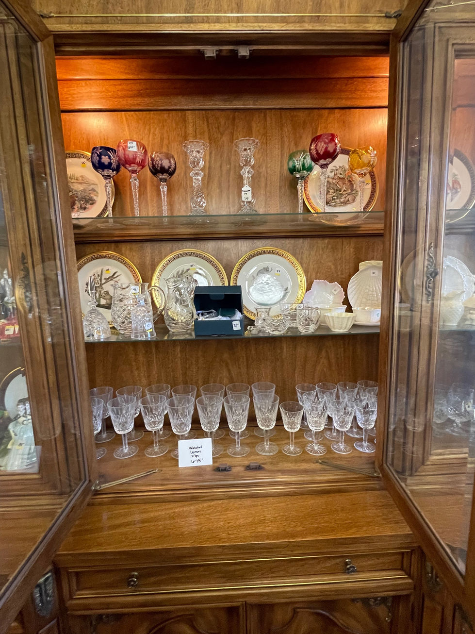 a display case with plates and glasses and a sign that says ' antique ' on it