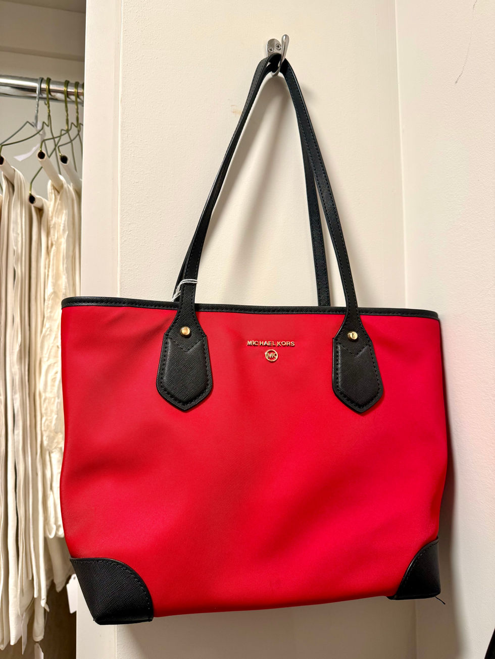 Red tote bag with black handles hanging up.