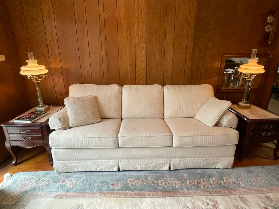 a white couch is in a room with wood paneling