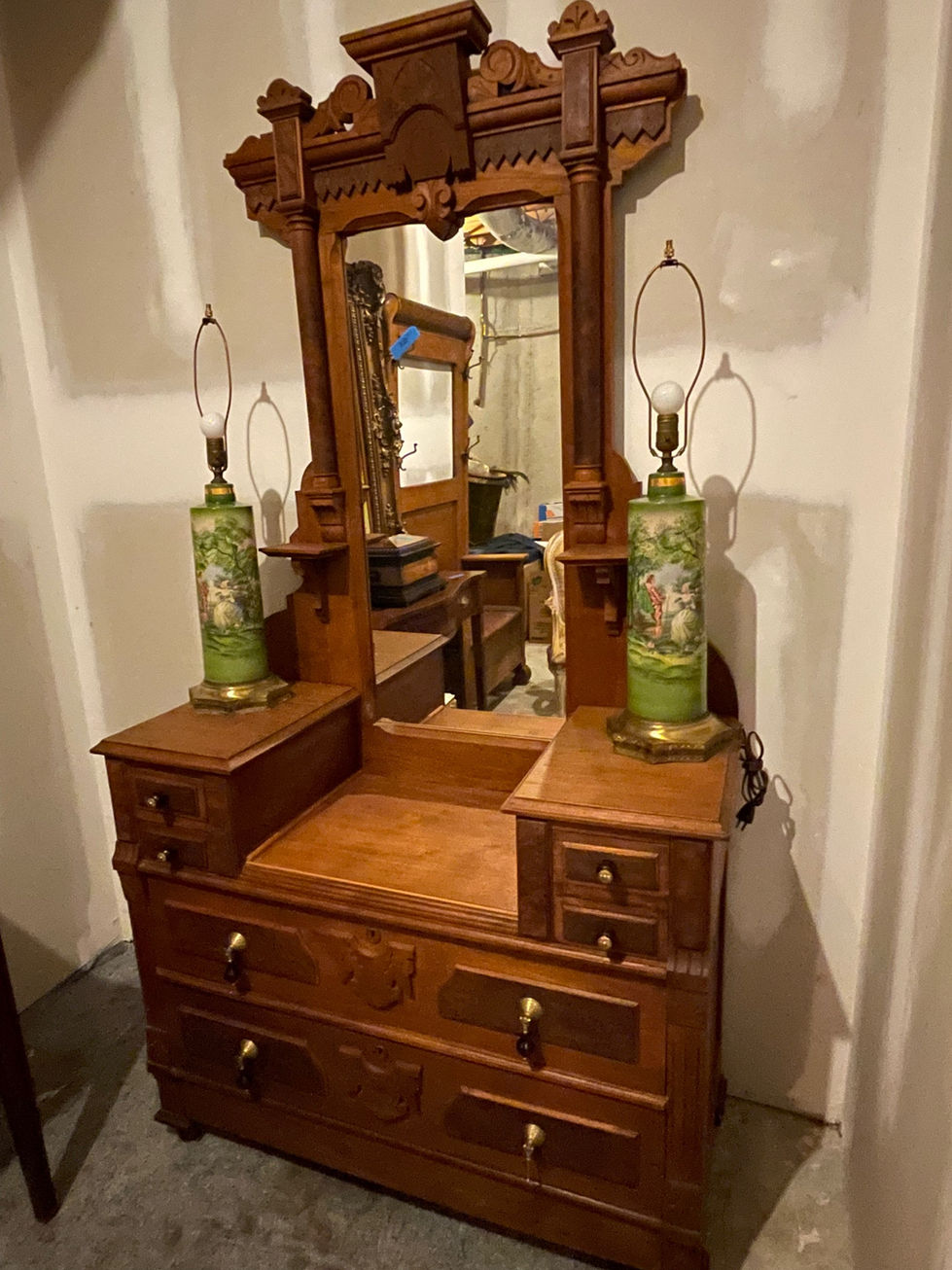 a wooden dresser with two green lamps and a mirror