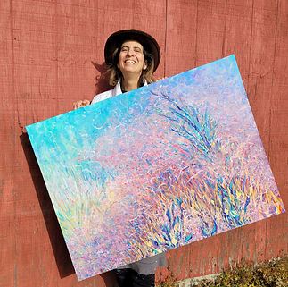 MaryAnn, the artist, holding a painitng ans smiling