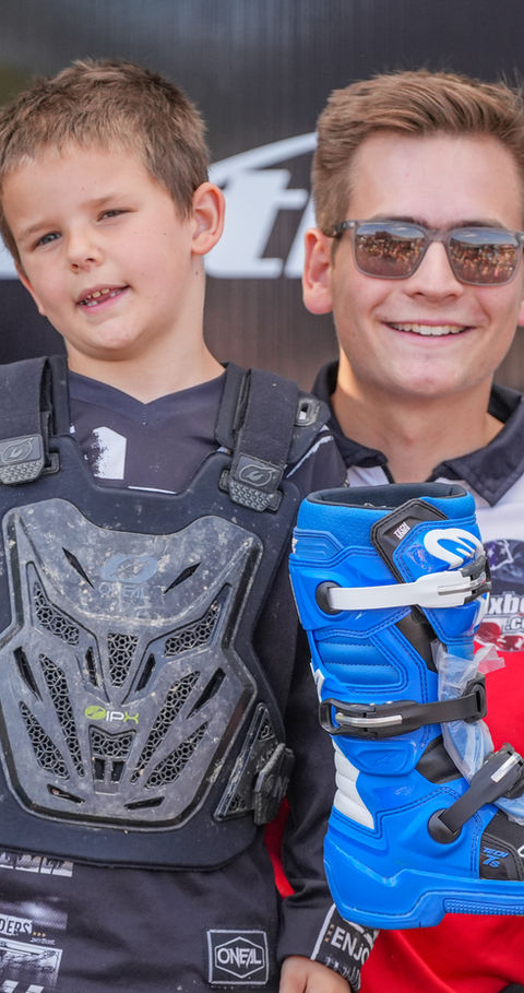 MxBoot.com giveaway winner with the owner holding a new pair of Alpinestars motocross boots at the track