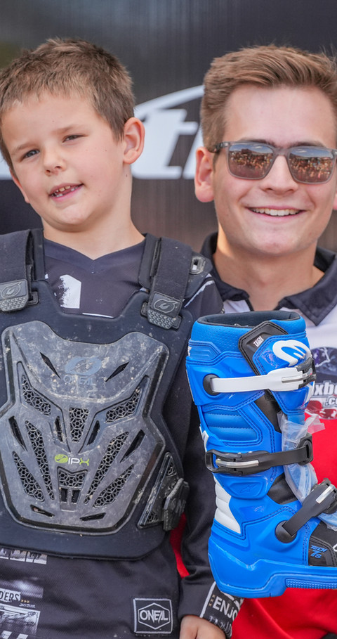 MxBoot.com giveaway winner with the owner holding a new pair of Alpinestars motocross boots at the track