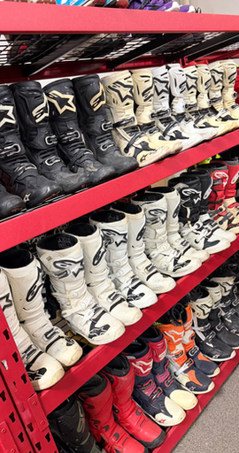 Assortment of used dirt bike boots in warehouse
