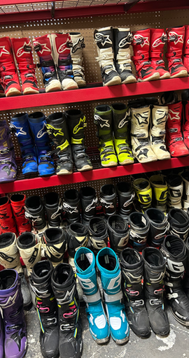 Used MX boots lined up on shelves for sale
