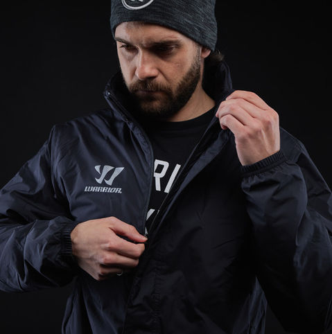 A man wears a Warrior jacket and text, Warrior sportswear. Professional hockey clothing, Ice Zone Pro.