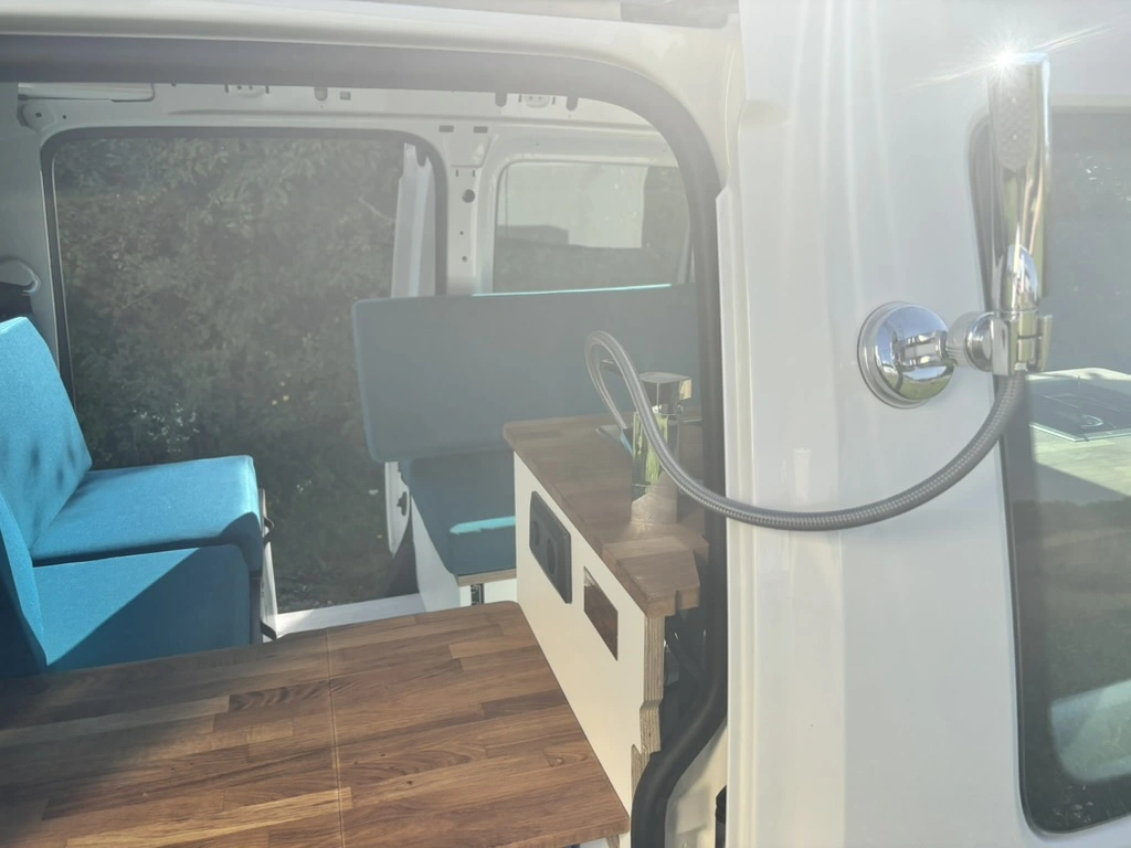 Claudia entspannt im fertigen Caddy Wohnmobil mit geöffneter Schiebetür