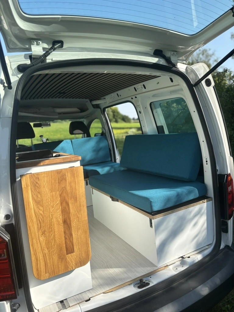 Innenansicht des ausgebauten Caddy als gemütliches Wohnmobil mit Küchenzeile