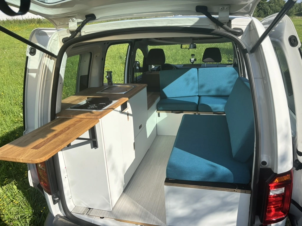Innenansicht des ausgebauten Caddy als gemütliches Wohnmobil mit Küchenzeile