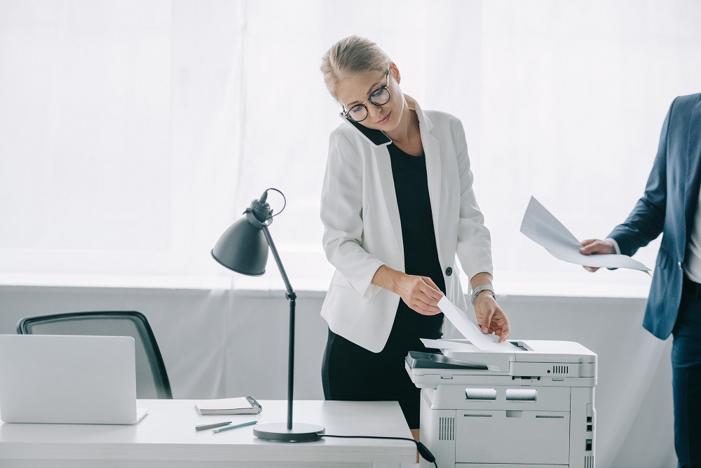 Woman on phone pulling papers off printer