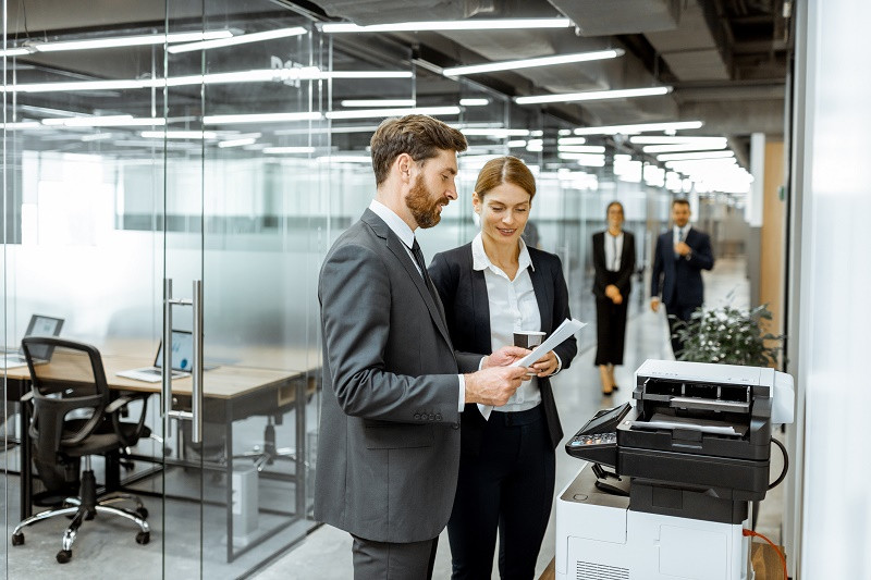 Man and woman standing at office printer