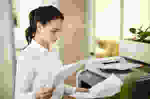 Young woman with papers by copy machine