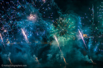 Blue and green fireworks exploding at night