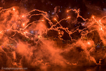 Orange and red fireworks light up the night sky