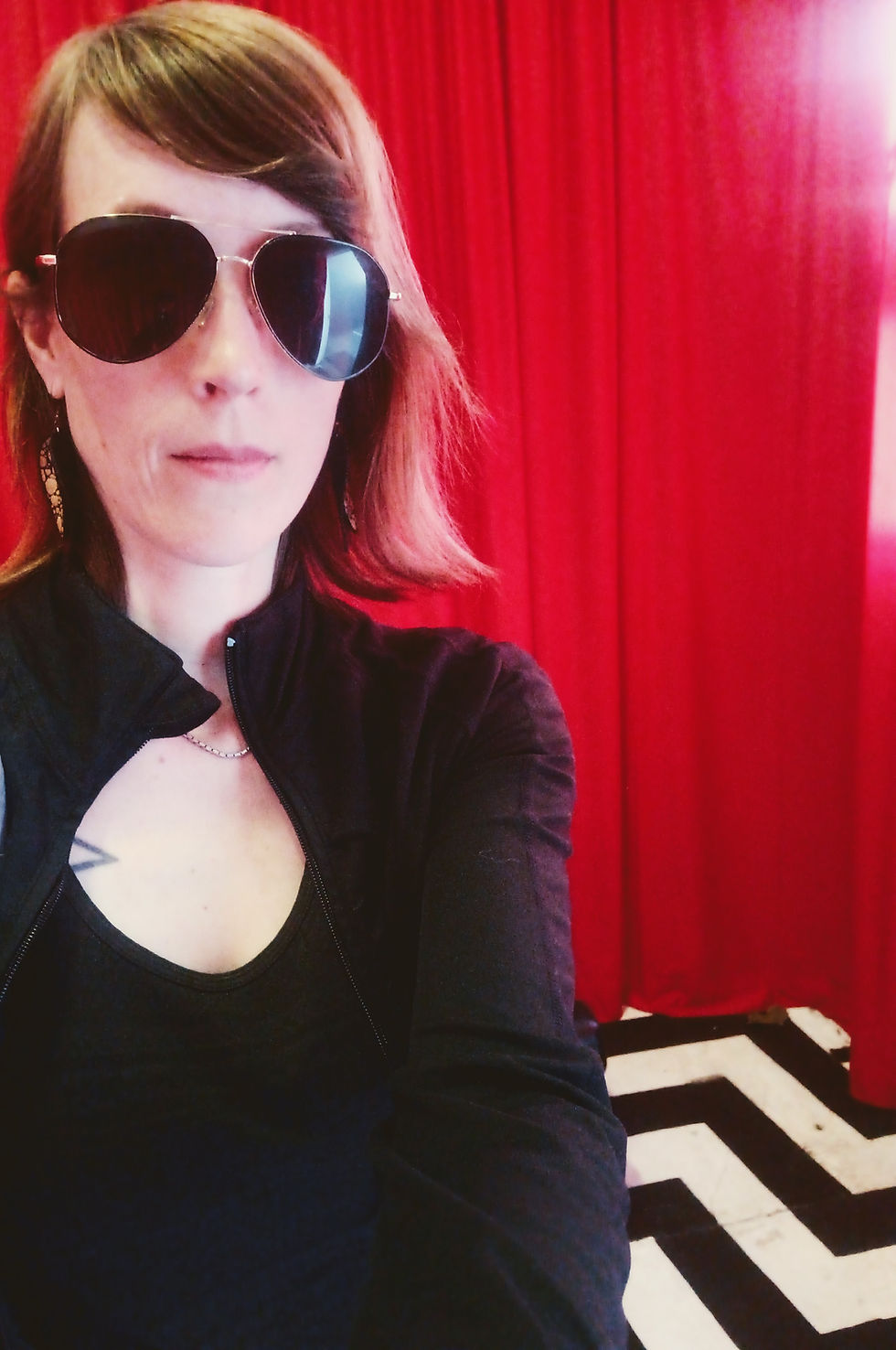 Fawn with sunglasses with a red curtain backdrop and chevron patterned floor