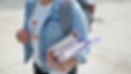 Woman walking with a backpack and books in her arms - student finance payment dates