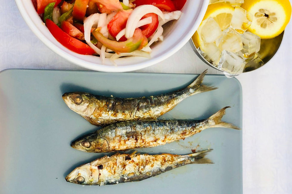 mackerel on a plate next to a bowl of lemon and a bowl of salad