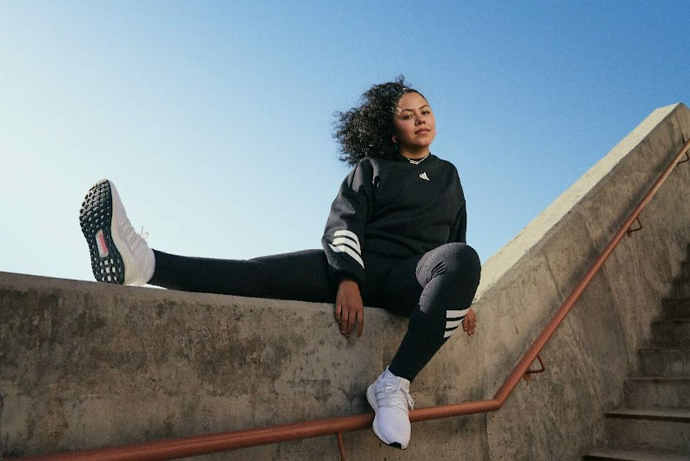 woman sat on top of a wall wearing Adidas clothes and trainers
