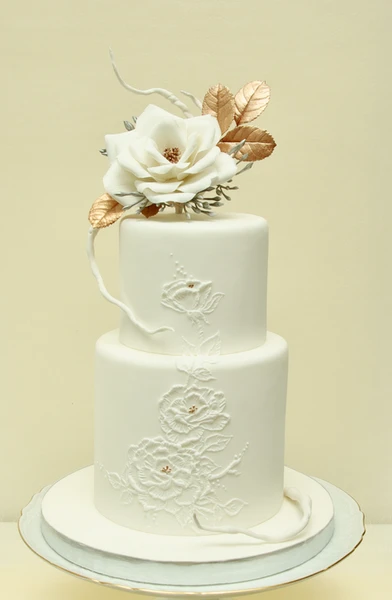 Bílý potahovaný dort zdobený cukrovými modelovanými květinami