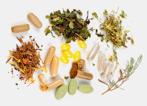 Pills and herbs spread on a white background, representing natural supplements.