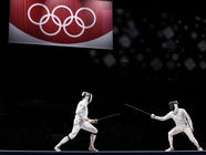 Two fencers dwarfed by the Olympic rings
