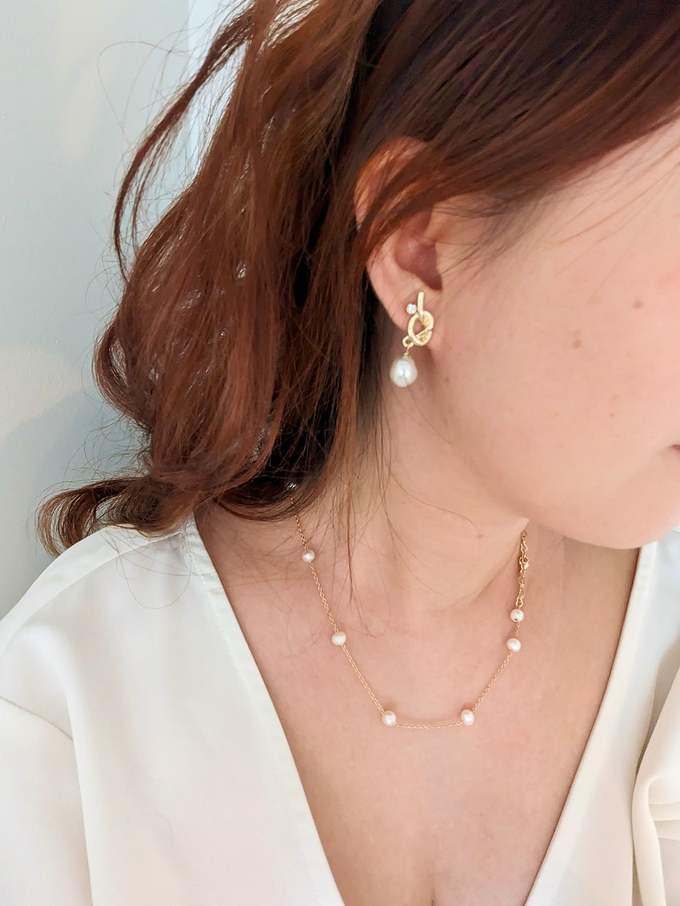A woman wearing pretty pearls necklace and earrings.