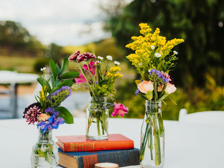 A stunning outdoor wedding reception table at Hope Springs Farm with thrift store books, random vases, and local flowers near Springfield, Missouri.
