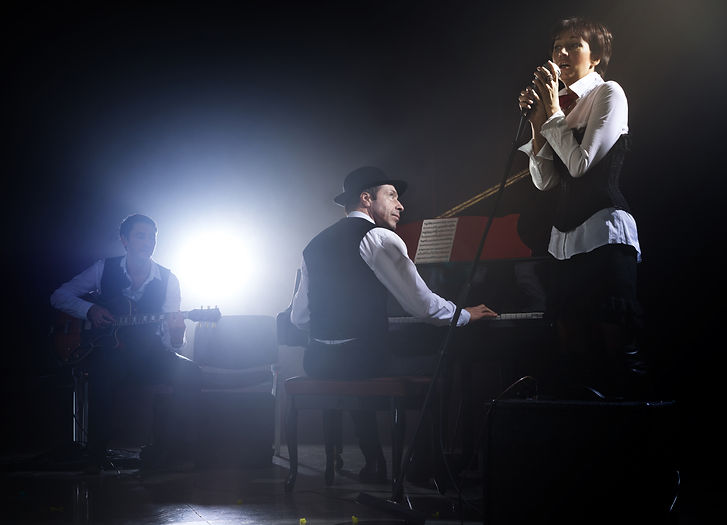 Girl singing into retro microphone to the accompaniment of piano and guitar.jpg