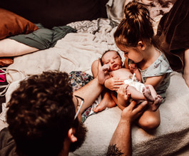 Big sister holding new baby immediately after birth. Sibling birth photography in Spokane, WA