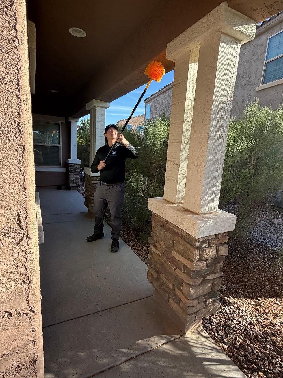 Pest control technician applying treatment around house perimeter in Arizona