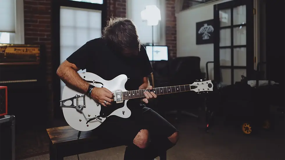 Michael Pope playing a white hollow-body electric guitar