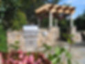 A patio with a grill and a pergola.