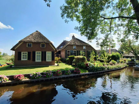 Een mooie foto van de gracht in Giethoorn met oude huisjes op de achtergrond