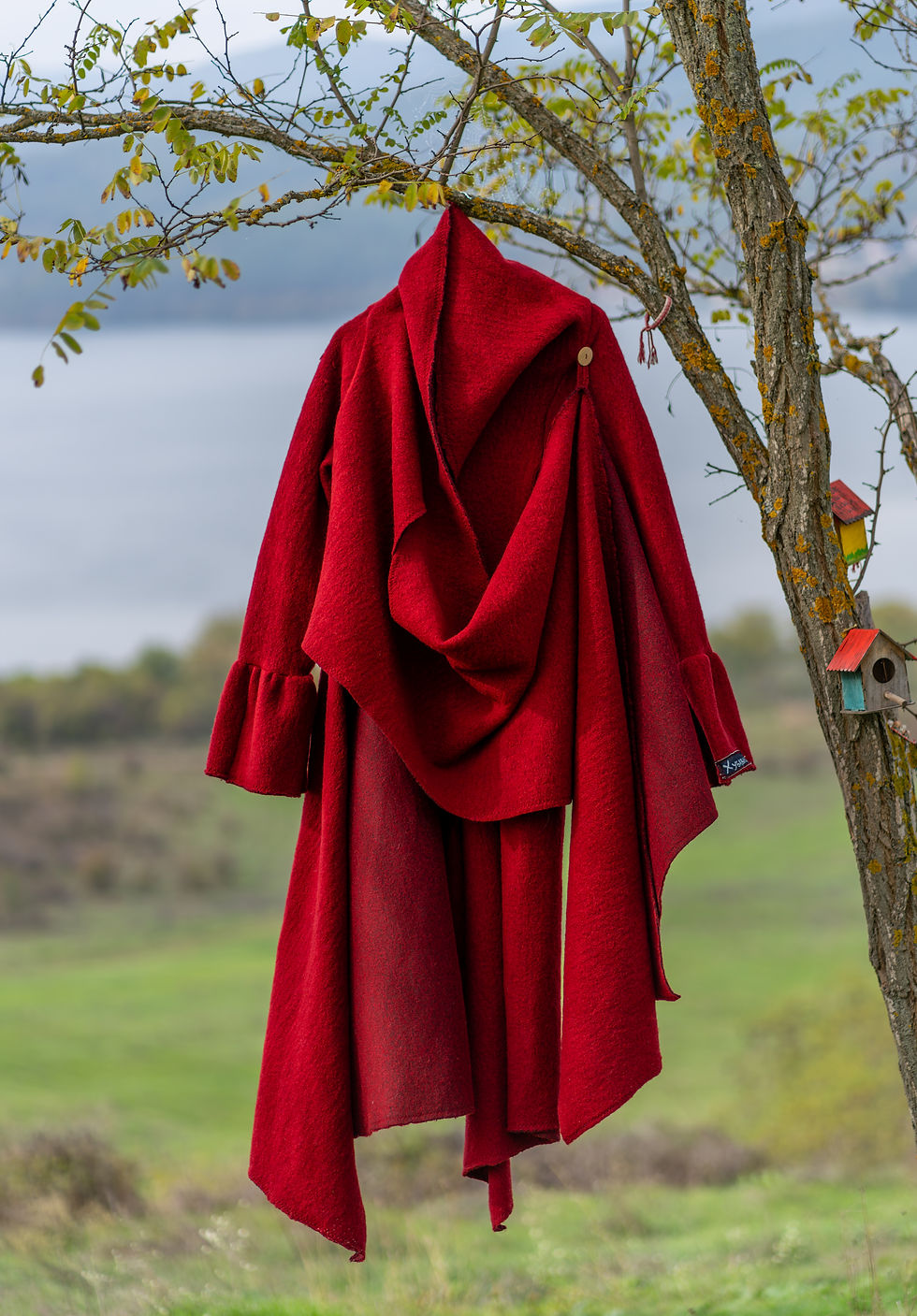 дълго червено палто, закачено на цъфнало дръвче