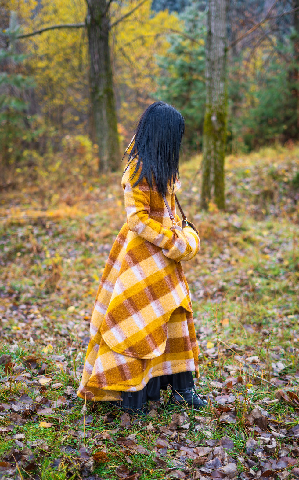 Хубавица е облечена в дълго палто в оранжево и кафяво с маншон с кожена каишка