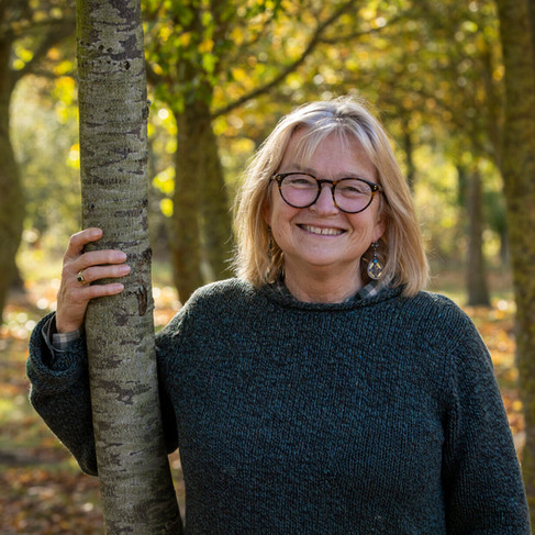 Smiling lady with glasses stood in a wood.