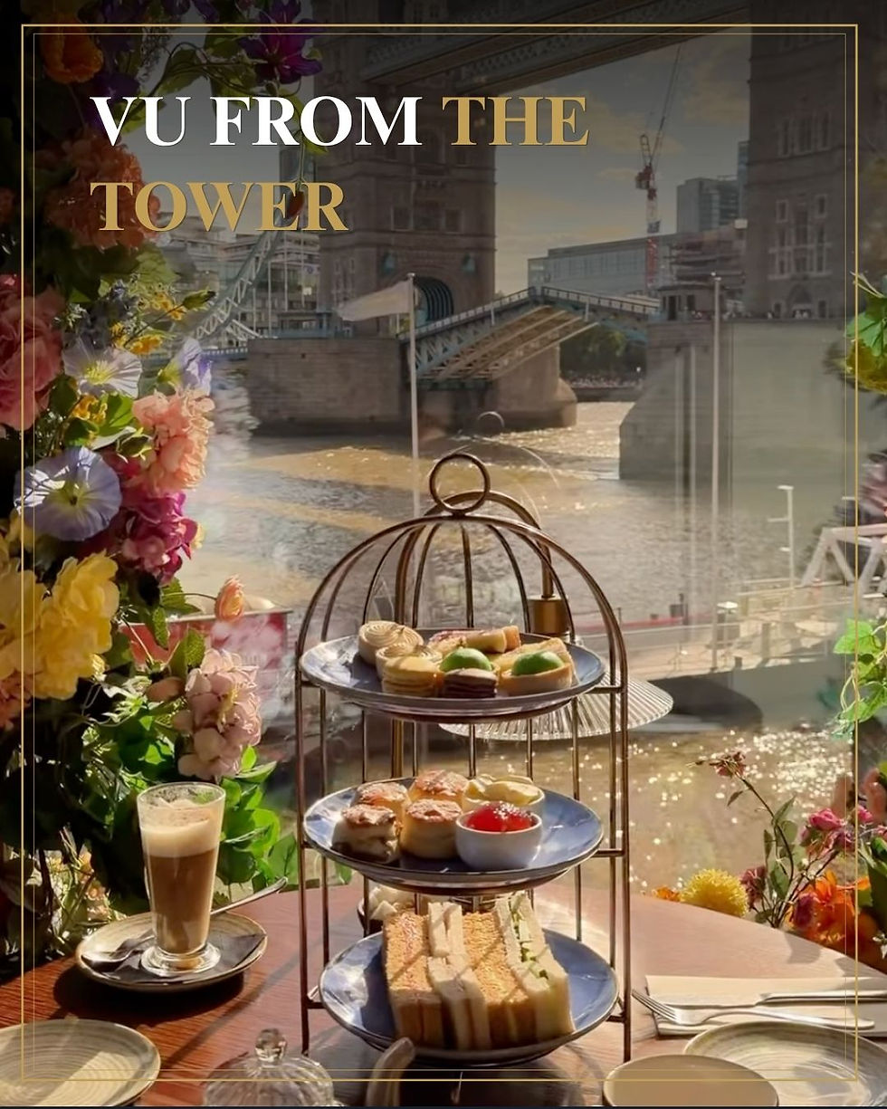 Bovenop Tower Bridge met etagère vol sandwiches en gebak, latte en bloemen; tekst: VU FROM THE TOWER.