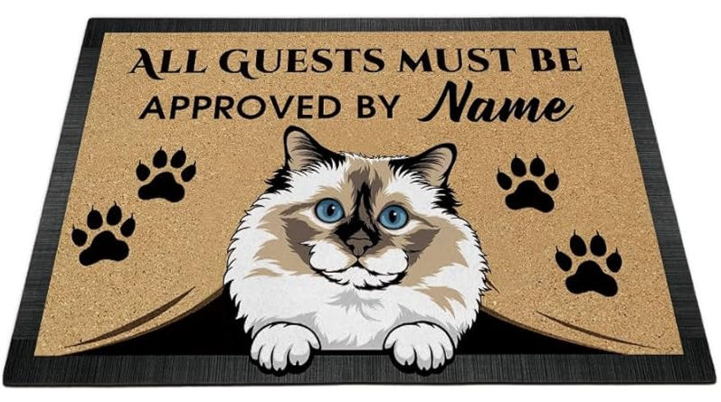 Cat-themed doormat with text "All guests must be approved by Name," featuring a cat illustration and paw prints on a beige and black background.