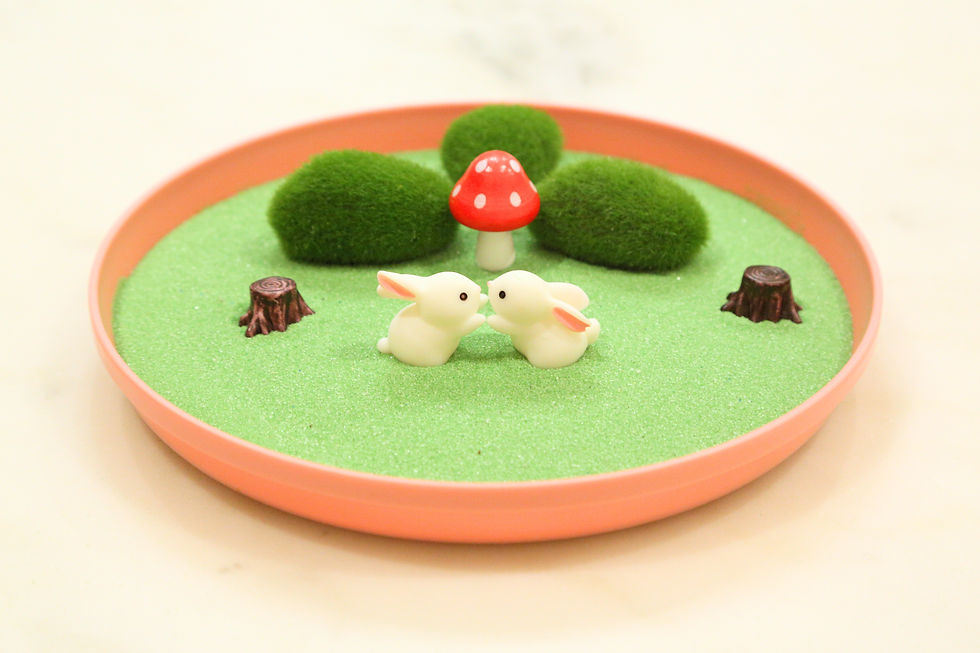 Thumbnail: Miniature white bunny figurines face each other on a small grassy display.