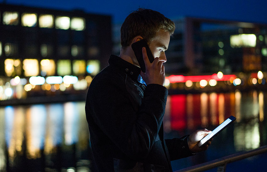 Executive checking messages on smartphone under city lights, symbolizing digital leadership in motion