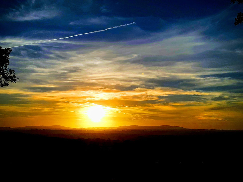 Close-up view of a smartphone screen showing a photo of a colorful sunrise over hills