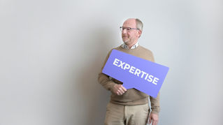 Un Manager Senior tenant une pancarte violette EXPERTISE