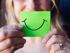 DRH tenant un post-it vert avec un smiley dessiné représentant sa satisfaction avec l'arrivée d'un DRH de transition.