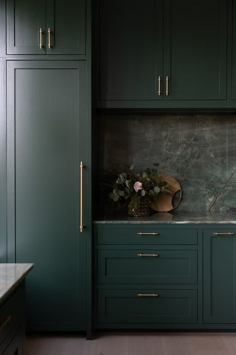 Modern dark green kitchen cabinets with gold handles.