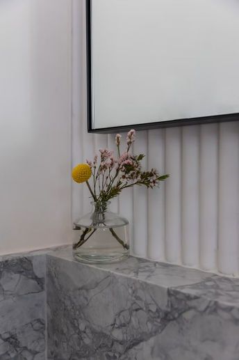 Yellow and pink flowers in a vase on a marble ledge
