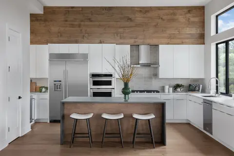 Modern kitchen with white cabinets, wood panel wall, and island